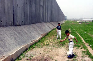 two children playing on the grass next to a giant wall